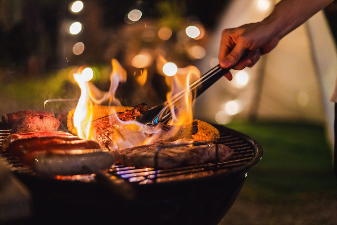 A flaming barbecue with meaty products on it
