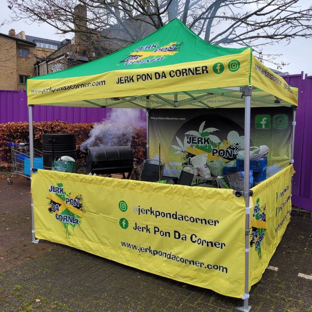 A printed pop up gazebo being used to sell Jamaican food