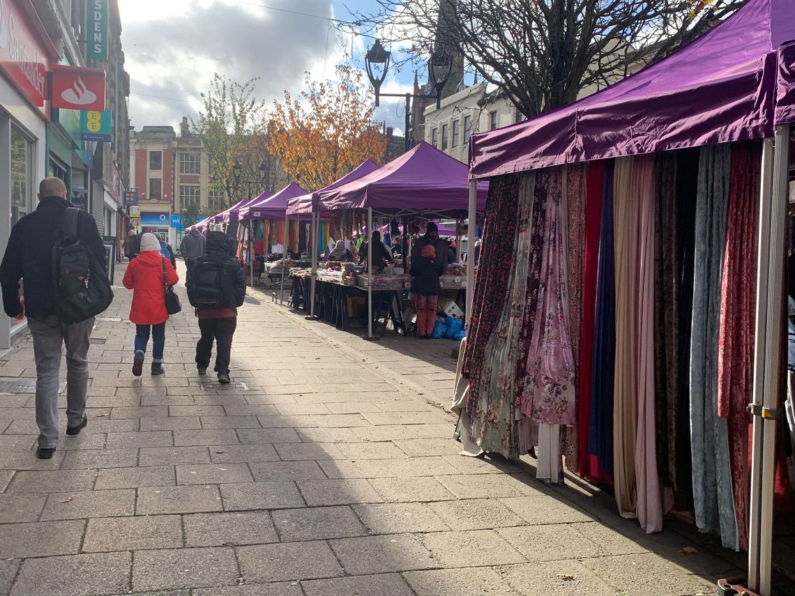 A row of purple pop-up gazebos used as market stalls