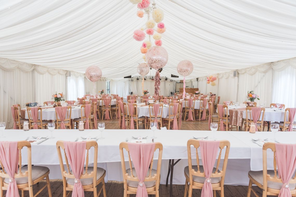 Empty tables and chairs in a decorated marquee ready for a wedding breakfast