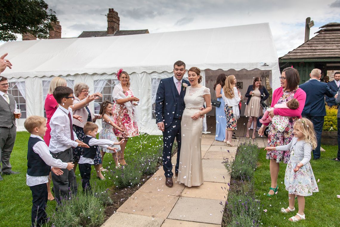 A happy couple leave a marquee wedding tent