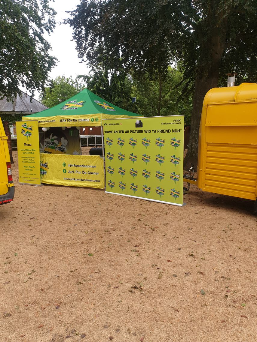 A gazebo with a printed canopy, sidewalls and banner at an outdoor event