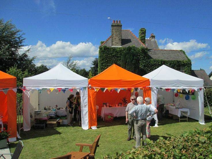 Multiple white and orange 3m x 3m pop up gazebos at a summer fete