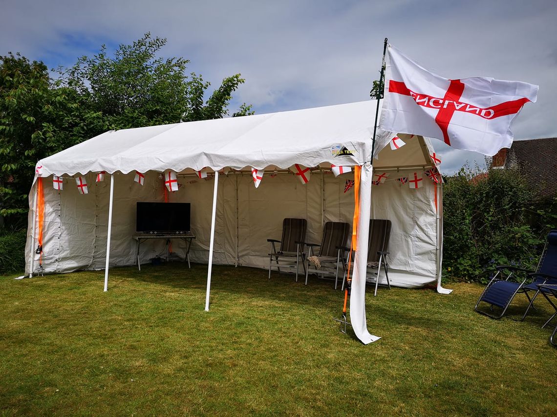 A white gala tent marquee adorned with St George cross buntings and an England flag