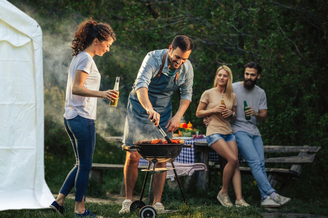 People having a barbecue next to a marquee