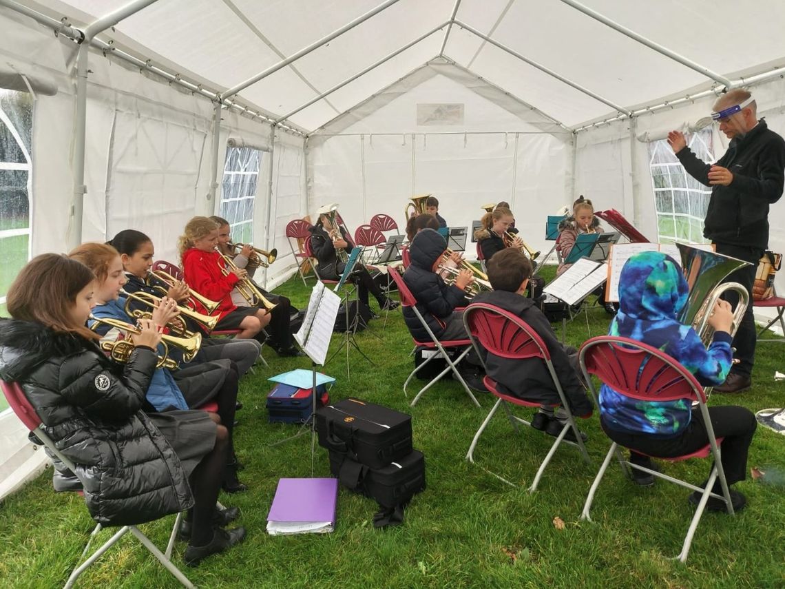 Children receive a music lesson beneath a marquee at a school