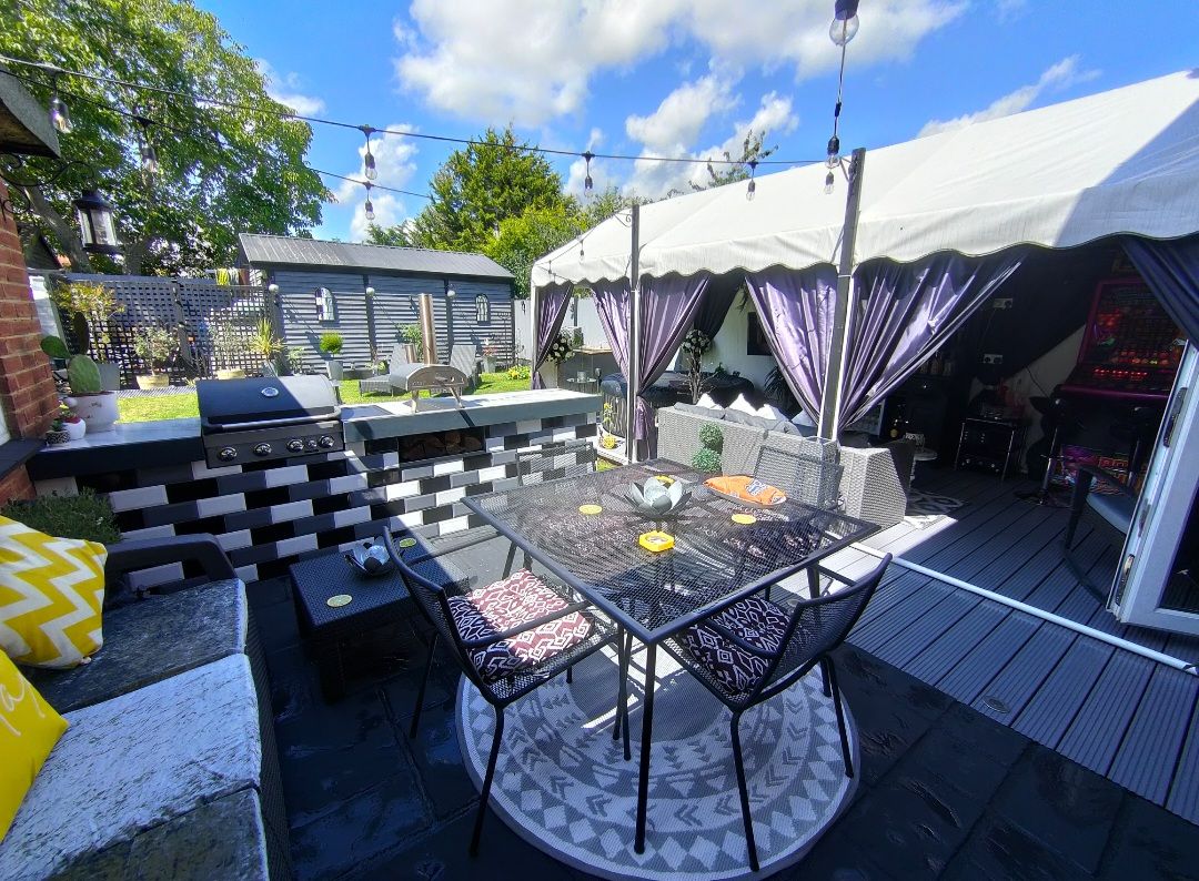 A marquee in a garden, on some decking. the tent has been decorated.