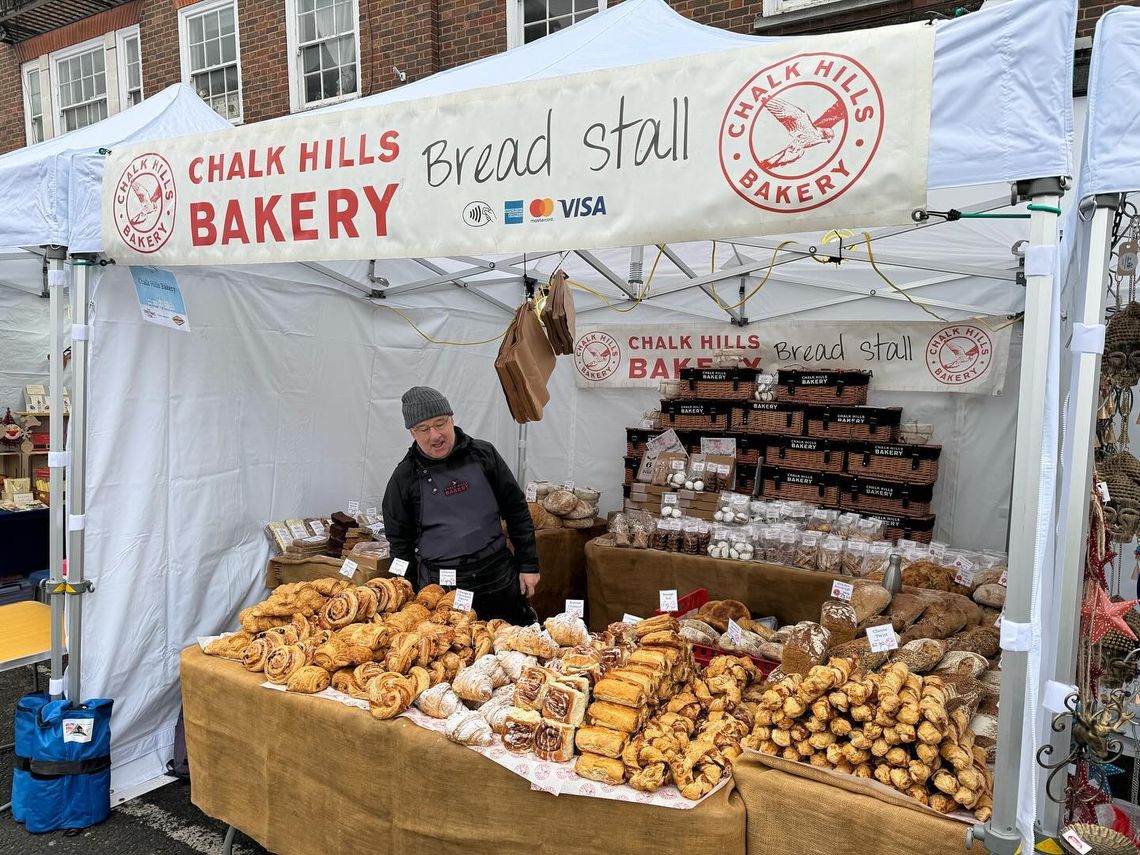 A man sells baked items beneath a white gazebo