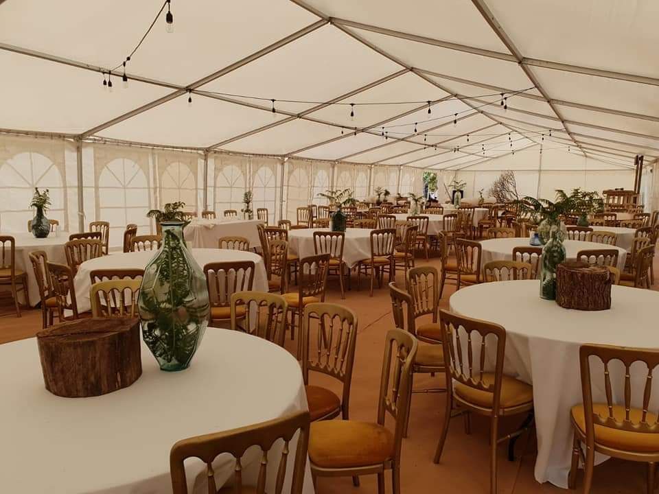 A large event marquee decorated with tables and chairs for an event