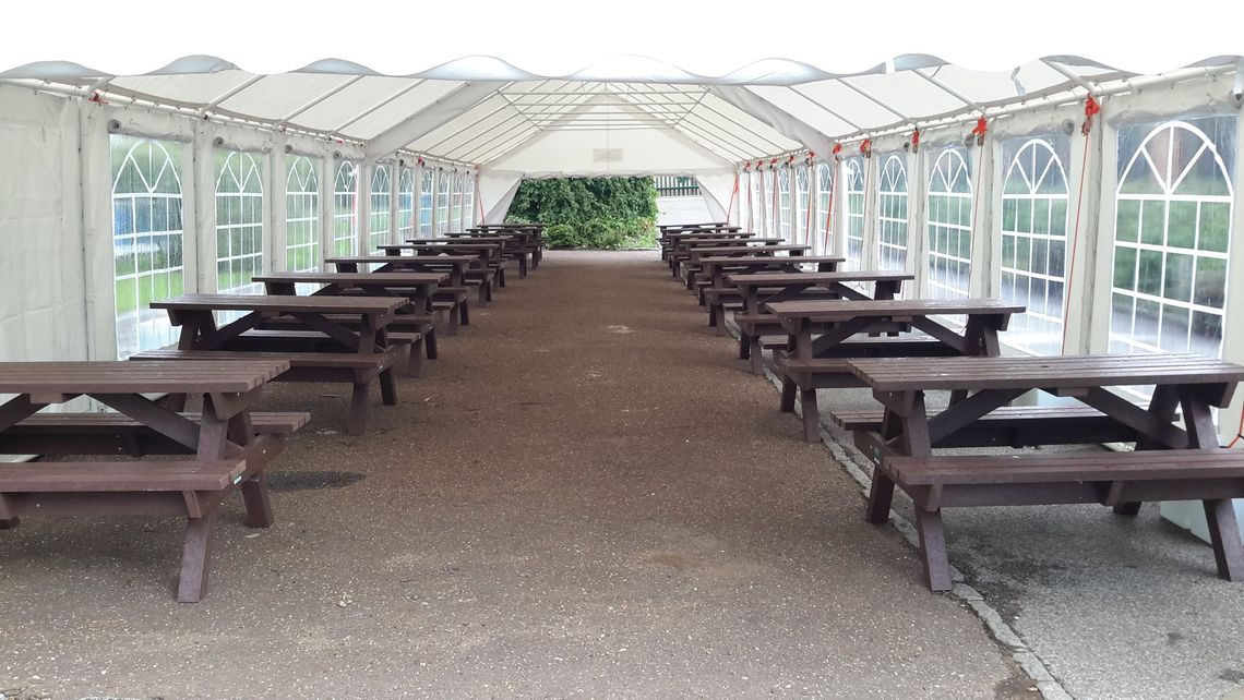 A theme park picnic area sheltered by a large Gala Tent marquee