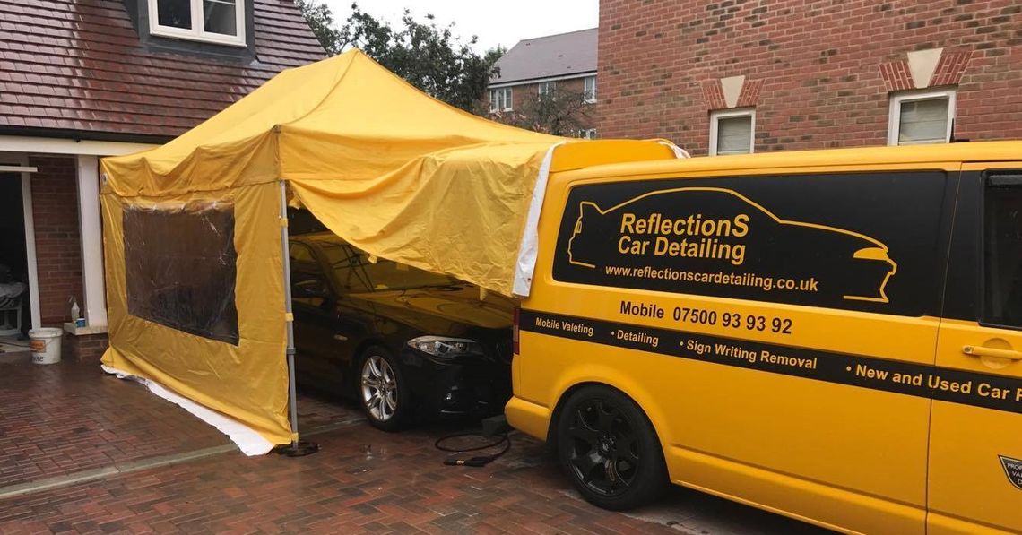 A yellow gazebo sheltering a car detailer