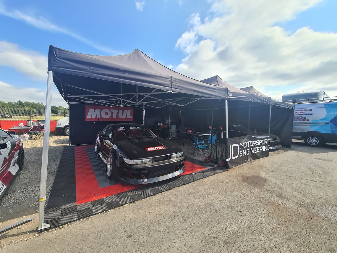 drift car on modular motorsport flooring beneath a gazebo