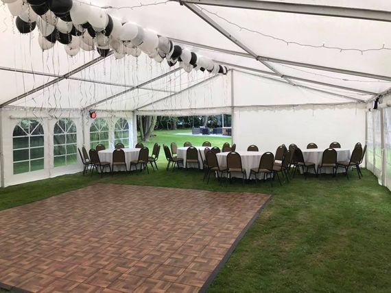large hire marquee with furniture an interior view of a decorated marquee with balloons, a dancefloor, chairs and tables