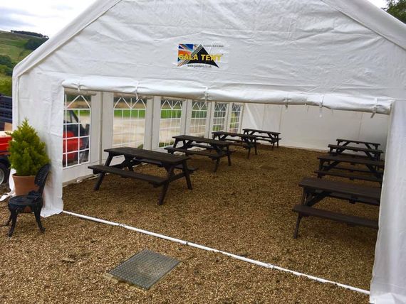 A white gala tent marquee sheltering outdoor benches in a pub garden