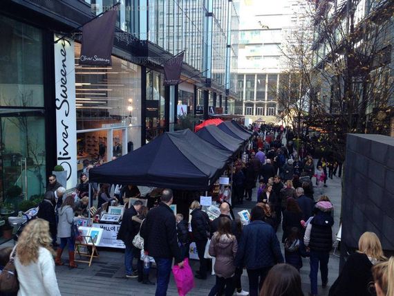 Black pop up gazebos at Southbank Market in London. There are lots of people around.