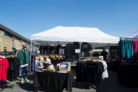 A white gazebo being used as shelter for a trade stall