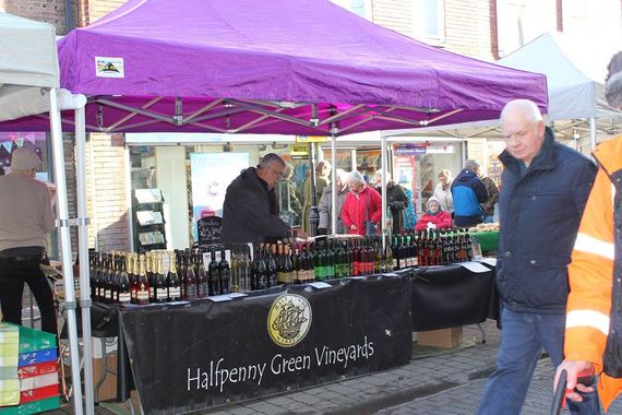 A purple gazebo being used for market trade selling wines