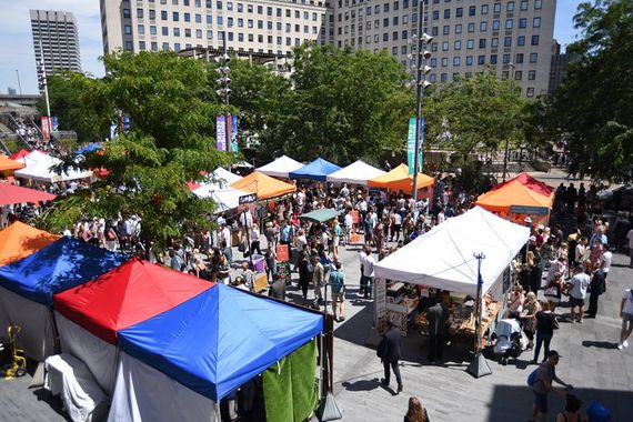 An outdoor market containing many trade gazebos and stalls