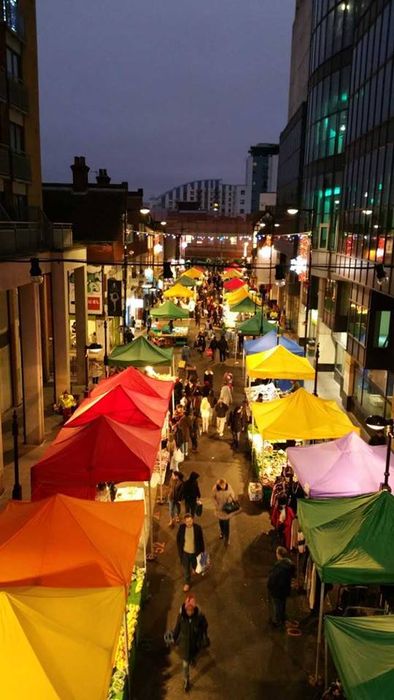 A street market containing many gazebos of a variety of colours