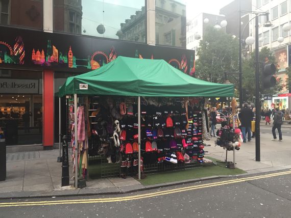A green gazebo being used as shelter for a street trader