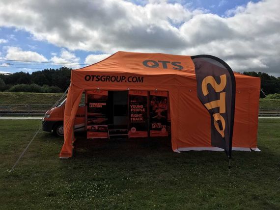 An orange gazebo and sidewalls branded with OTS Group