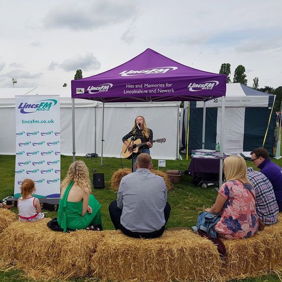A purple printed gazebo with a musician performing underneath at a country show