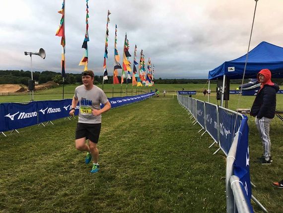 A picture of an athlete at a cross country event with a blue gazebo shelter standing offside