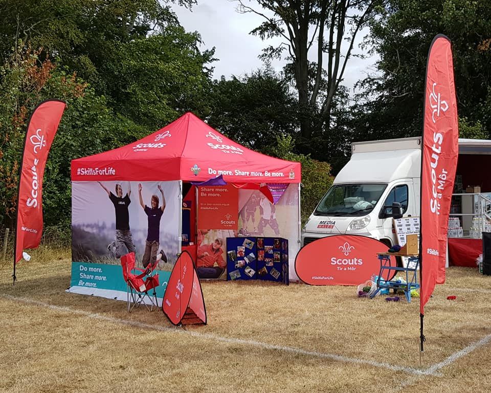 A Gala Shade printed gazebo at an outdoor scouting event with matching printed feather flags