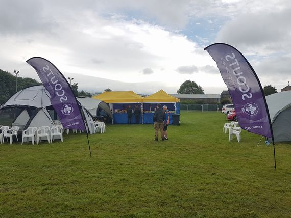 scouting flags A pair of blue and yellow Gala Shade gazebos at a scout event with two purple printed feather flags in the foreground