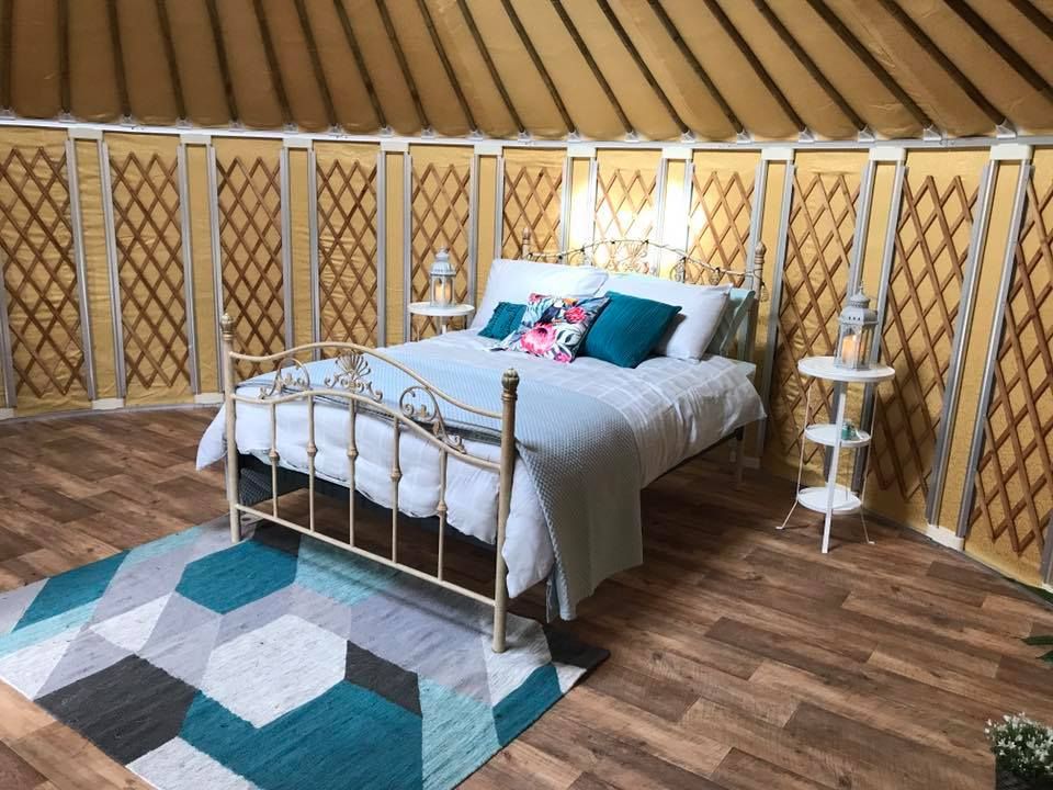 An interior view of a Mongolian glamping yurt with a double bed and wooden floor