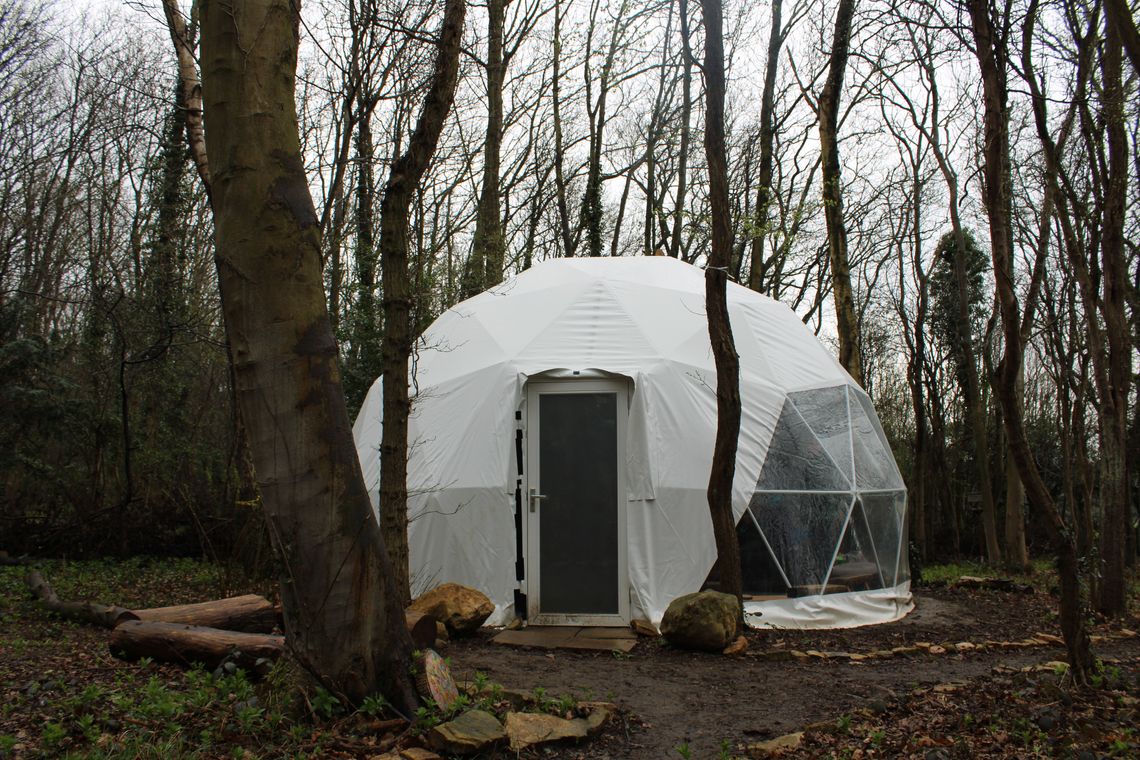 A Geodesic glamping dome tent set up in the woods