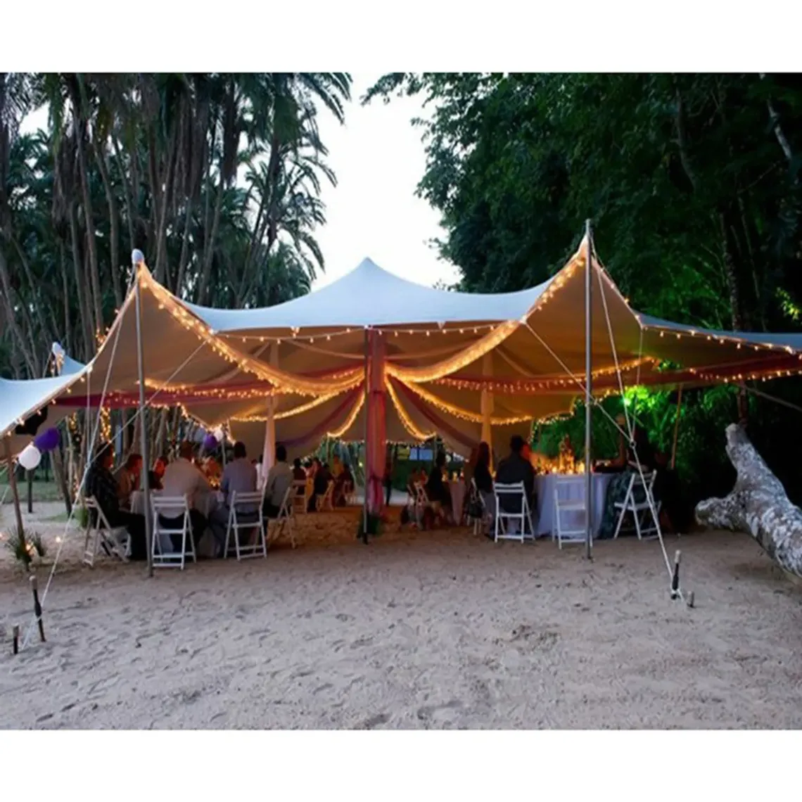 A stretch tent set up with lighting and outdoor furniture