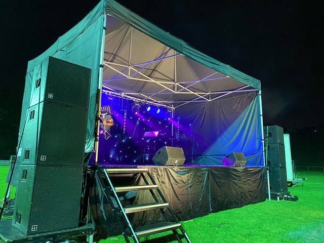 A green heavy duty gazebo over a small performance stage