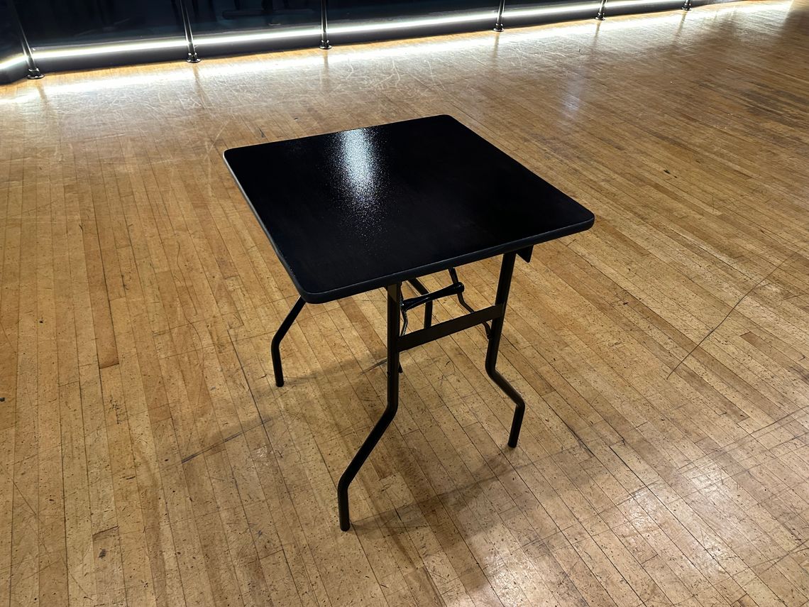 A small black banquet table on a dancefloor