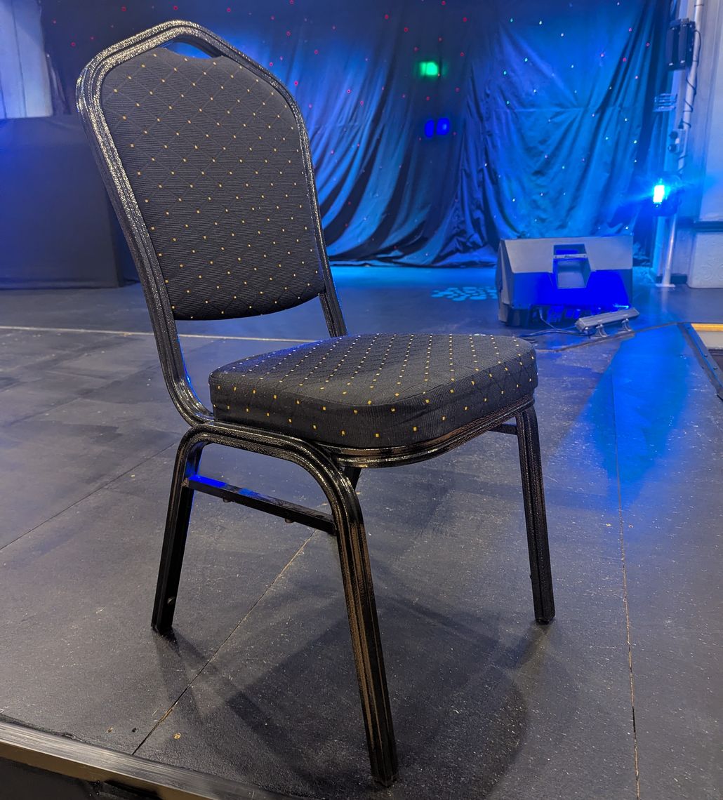 A black and gold banquet chair on a venue stage