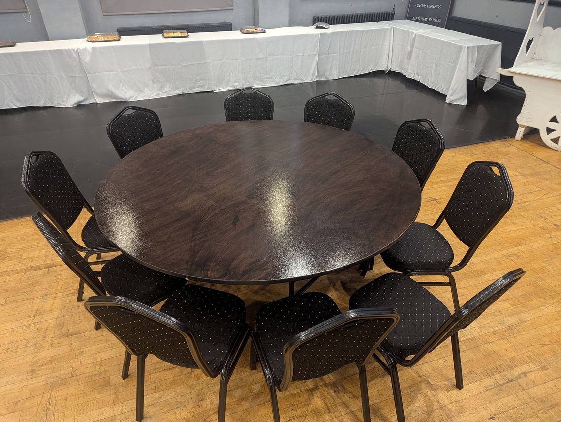 A large round conference table with chairs around it at a wedding venue